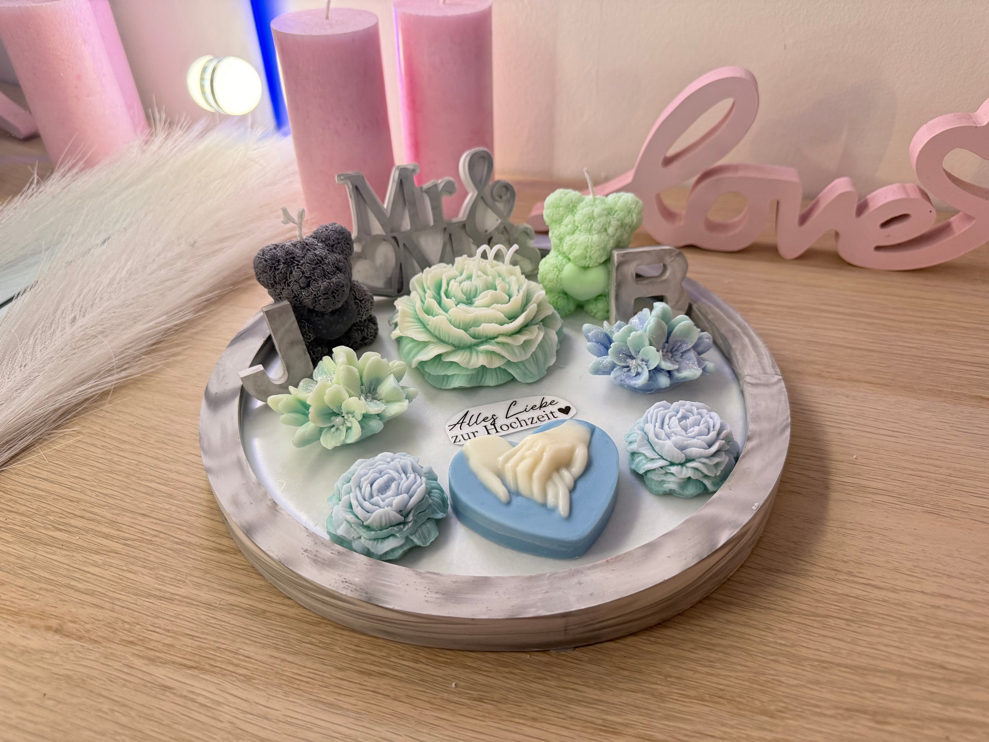 Handmade-Hochzeitsdeko mit pastellfarbenen Wachsblüten und personalisierbaren Initialen.