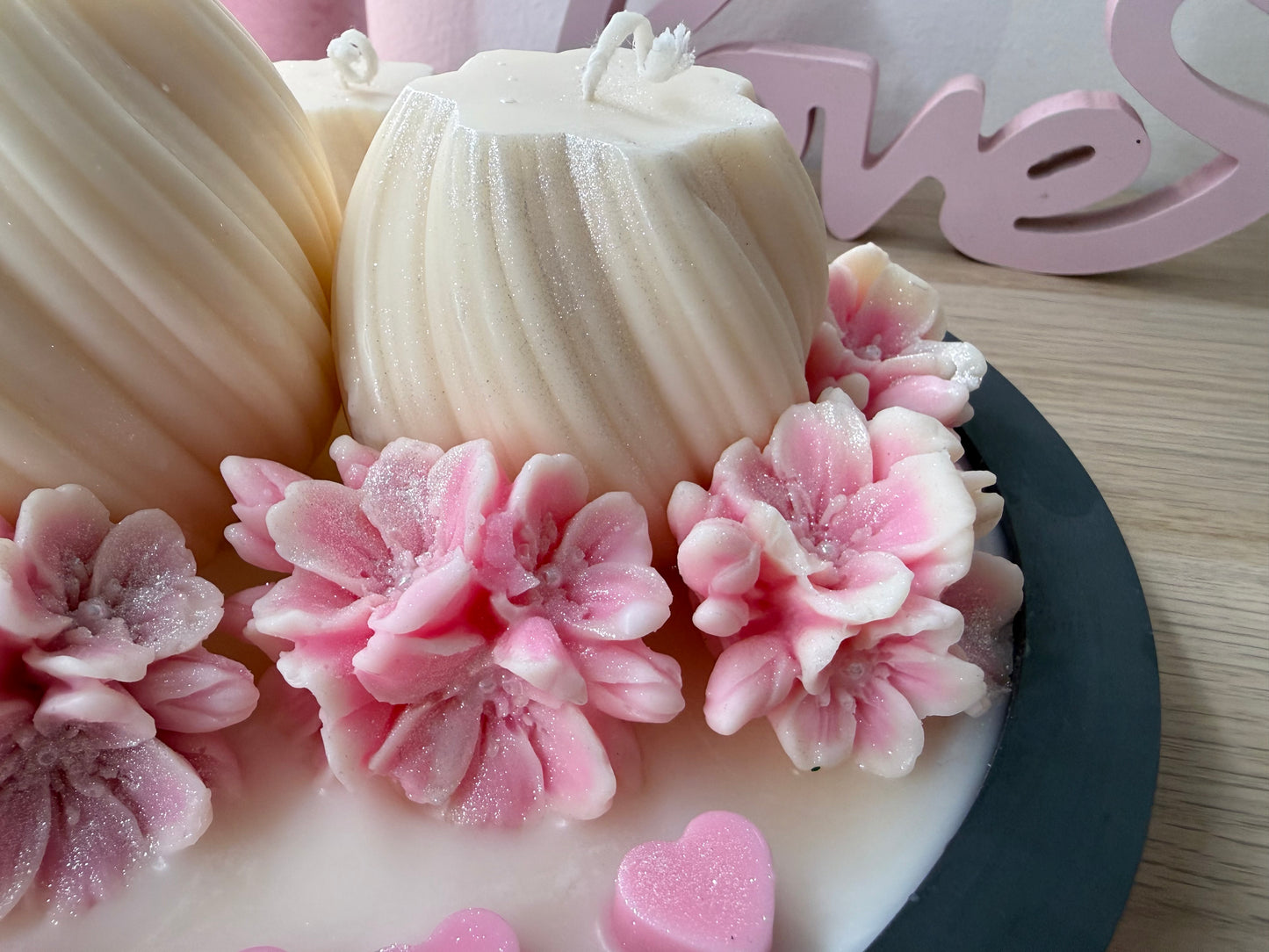 Detailfoto der handgefertigten Wachsblüten in Rosa und Weiß mit Glitzereffekt – filigrane Blumen in hochwertiger Kerzendekoration.