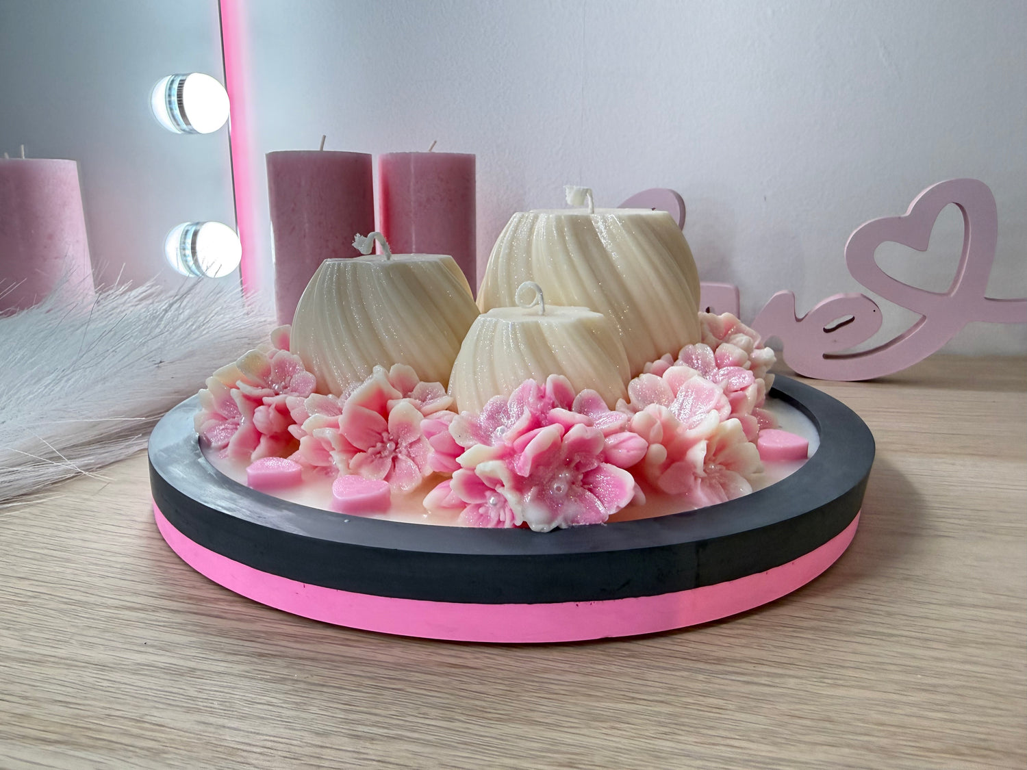 Luxus-Deko-Schale mit Kerzen und rosa Blüten aus Wachs, seitliche Nahaufnahme des detailreichen Blumenkranzes.